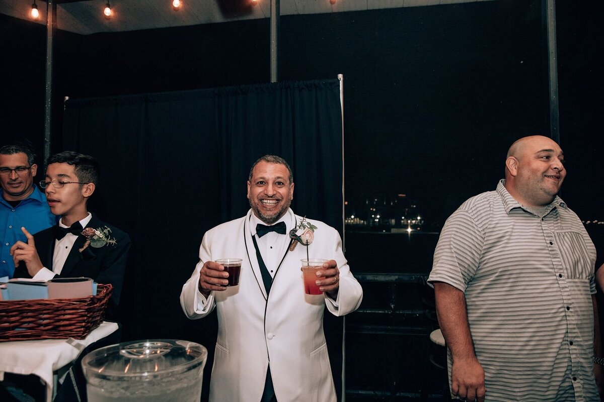 groom holding up his beverages for a photo