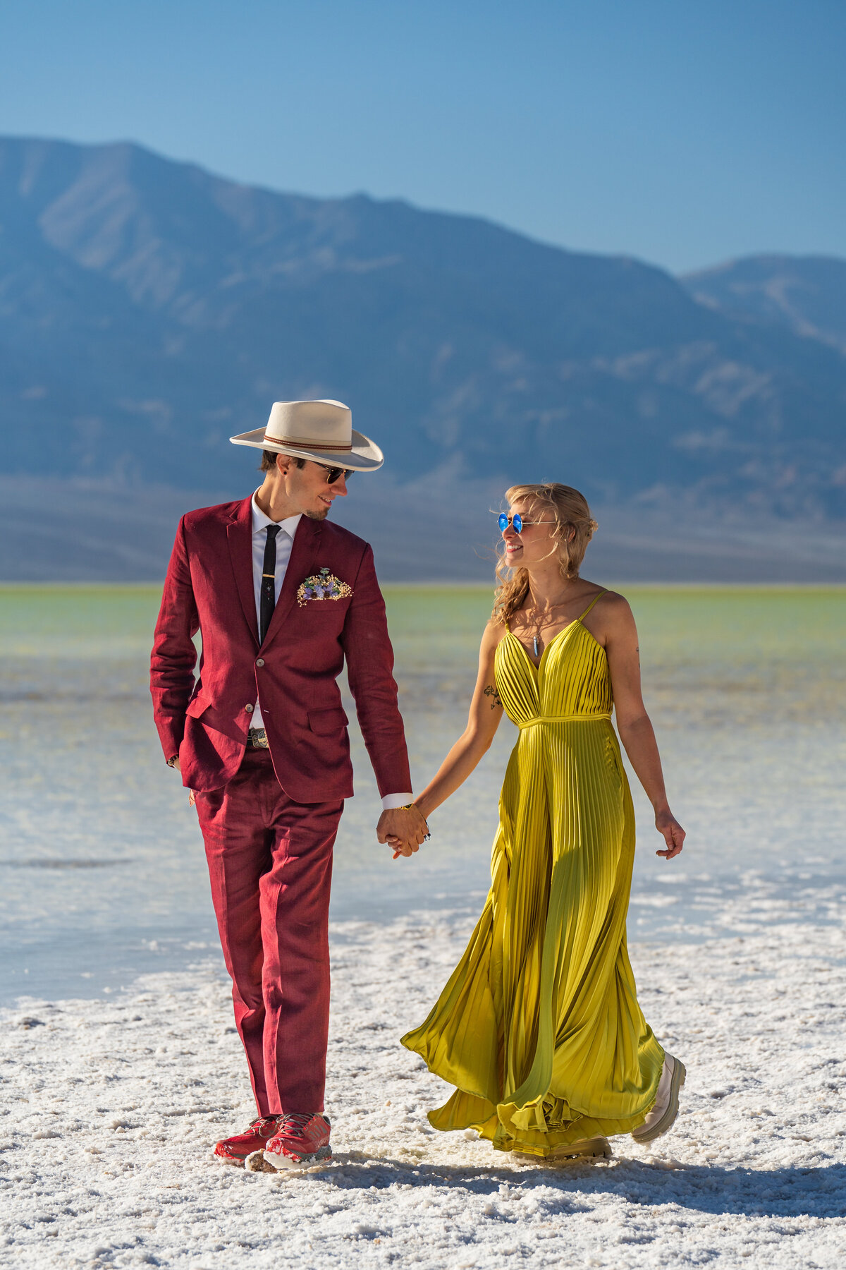 A couple holding hands and walking along salt flats