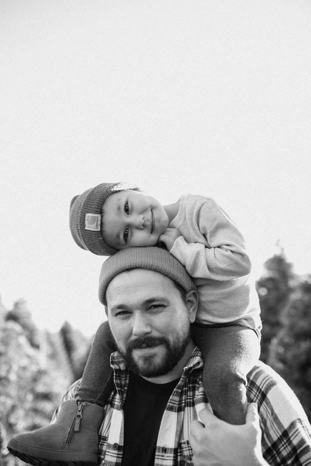 black and white image father holding son on shoulders