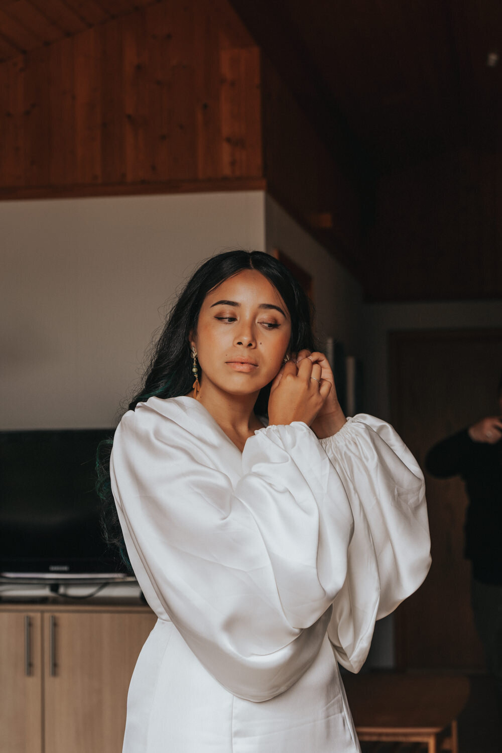 Bride puts on her earrings while getting ready 