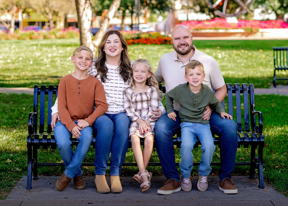 Parents and 3 children smiling together in a garden filled with green plants and flowers