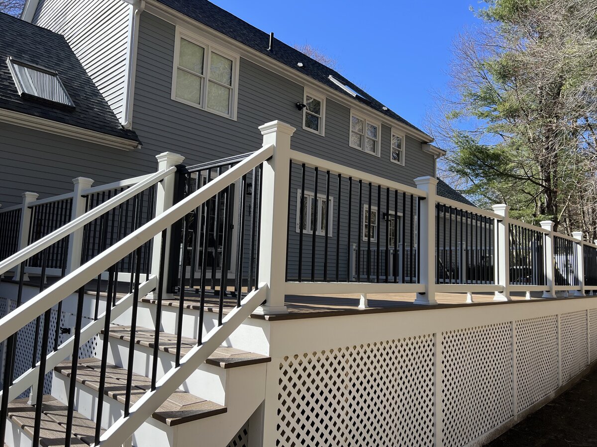 A deck with a PVC trellis face and handrails on a blue house built by a Worcester Deck Builder