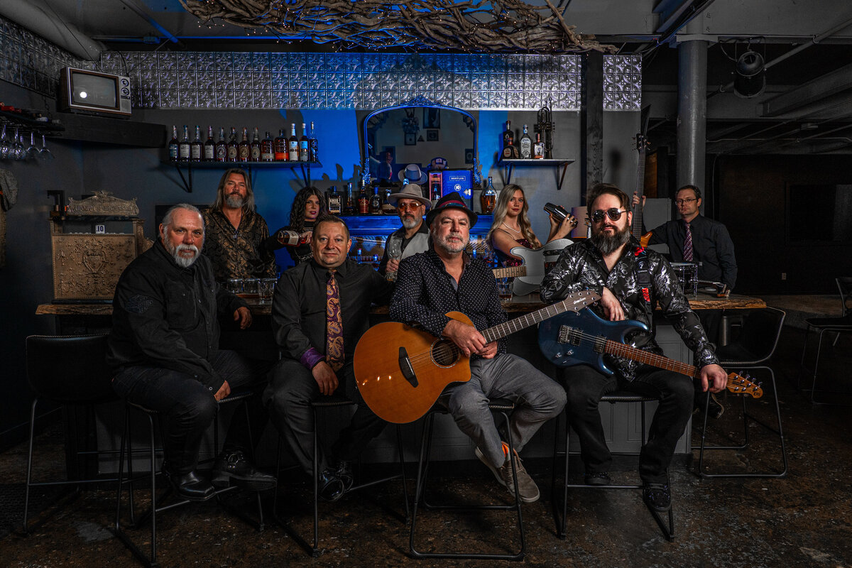 A band sitting and standing around a bar together 