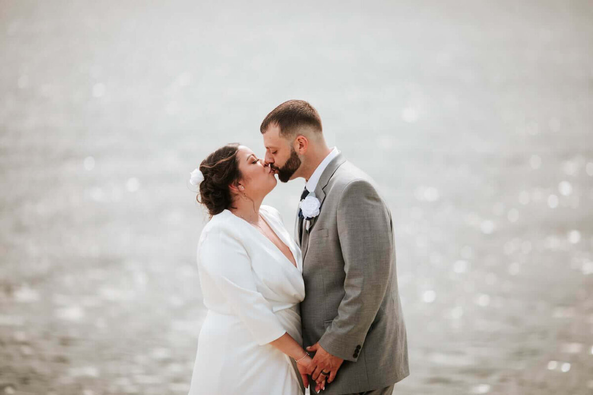 The bride and groom share an intimate moment in front of the water in hudson valley.