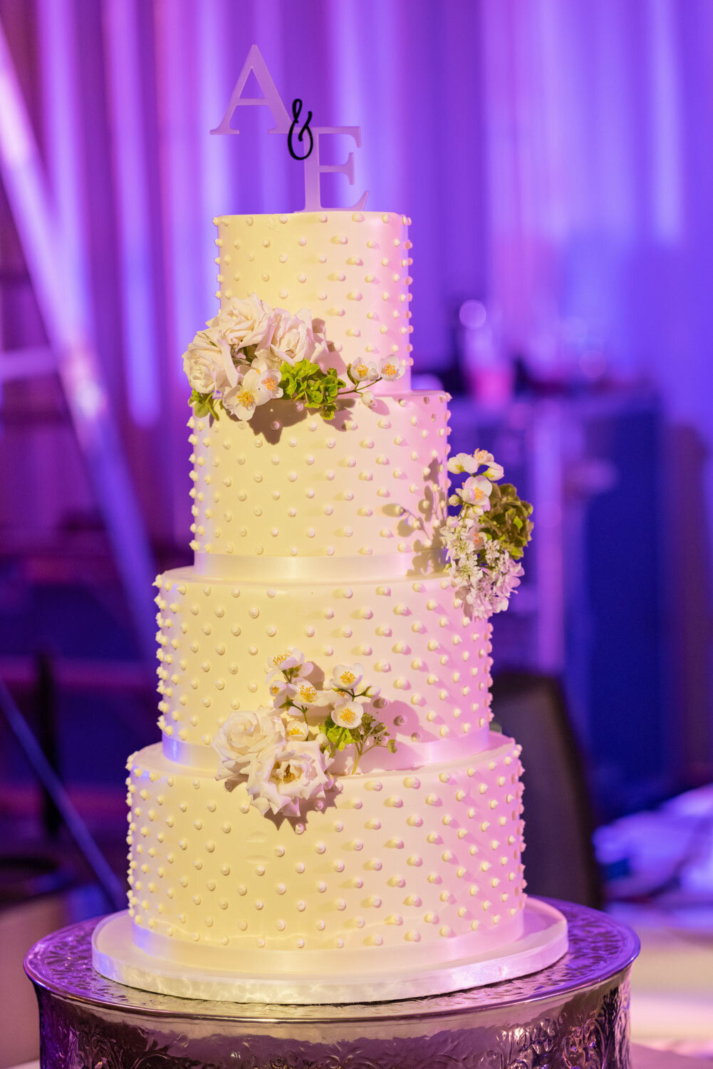 A wedding cake with flowers on it is sitting on a table.