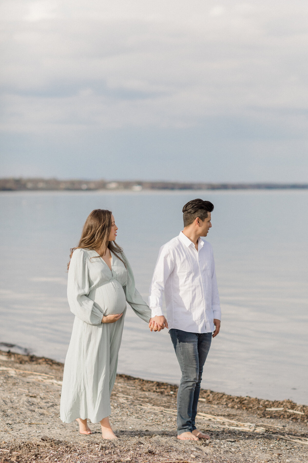 expecting couple holding hands at beach by Orlando maternity photographer.