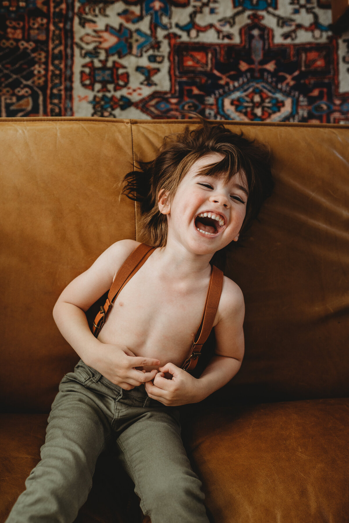 candid laughing of little boy in suspenders in tucson