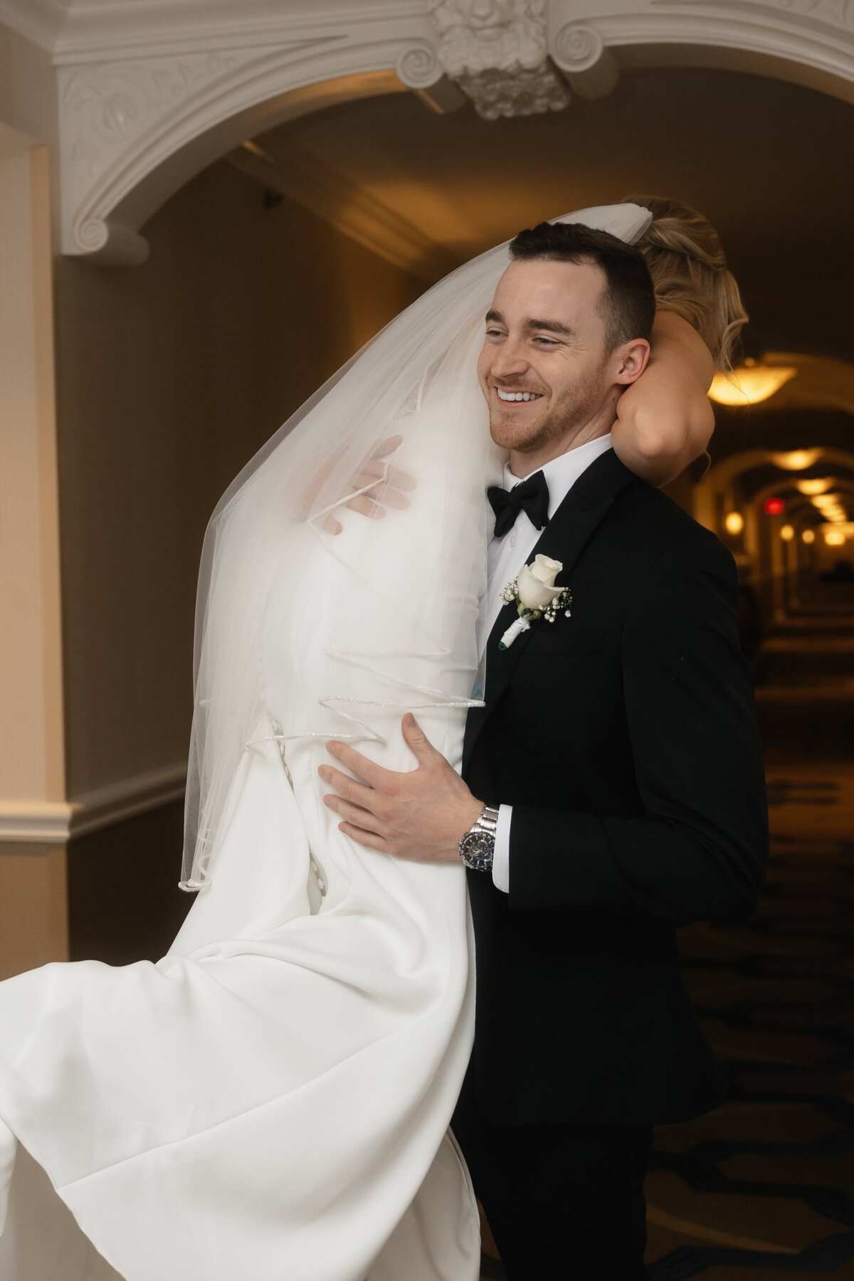 Groom carries bride down hallway before their wedding in vegas