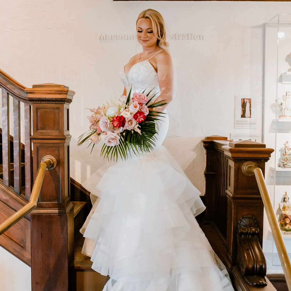 bride stands on wood staircase with tropical bouquet