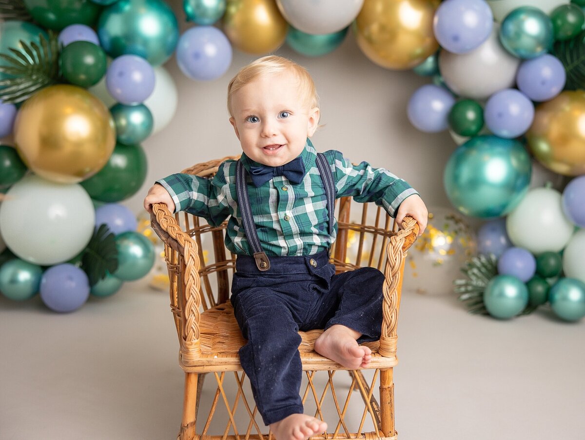 baby smiling in chair with plaid green shirt on