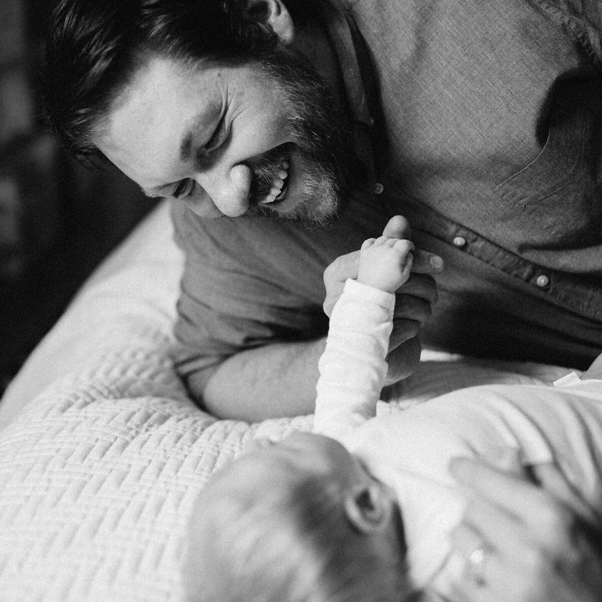 Black and white image of father looking at newborn son
