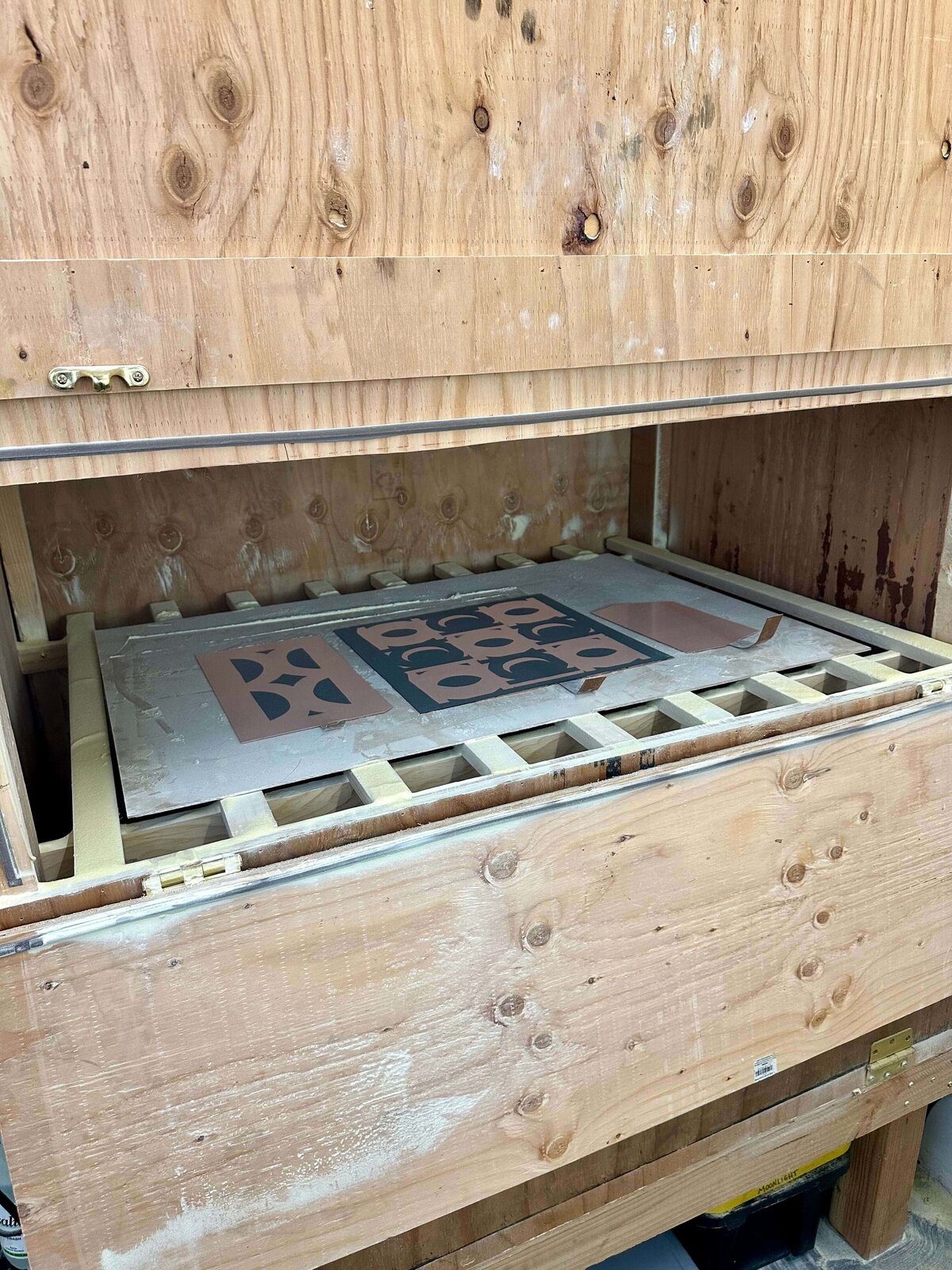 Copper plates inside a wooden rosin box, prepared with asphaltum designs, ready for aquatint rosin application and fusing.