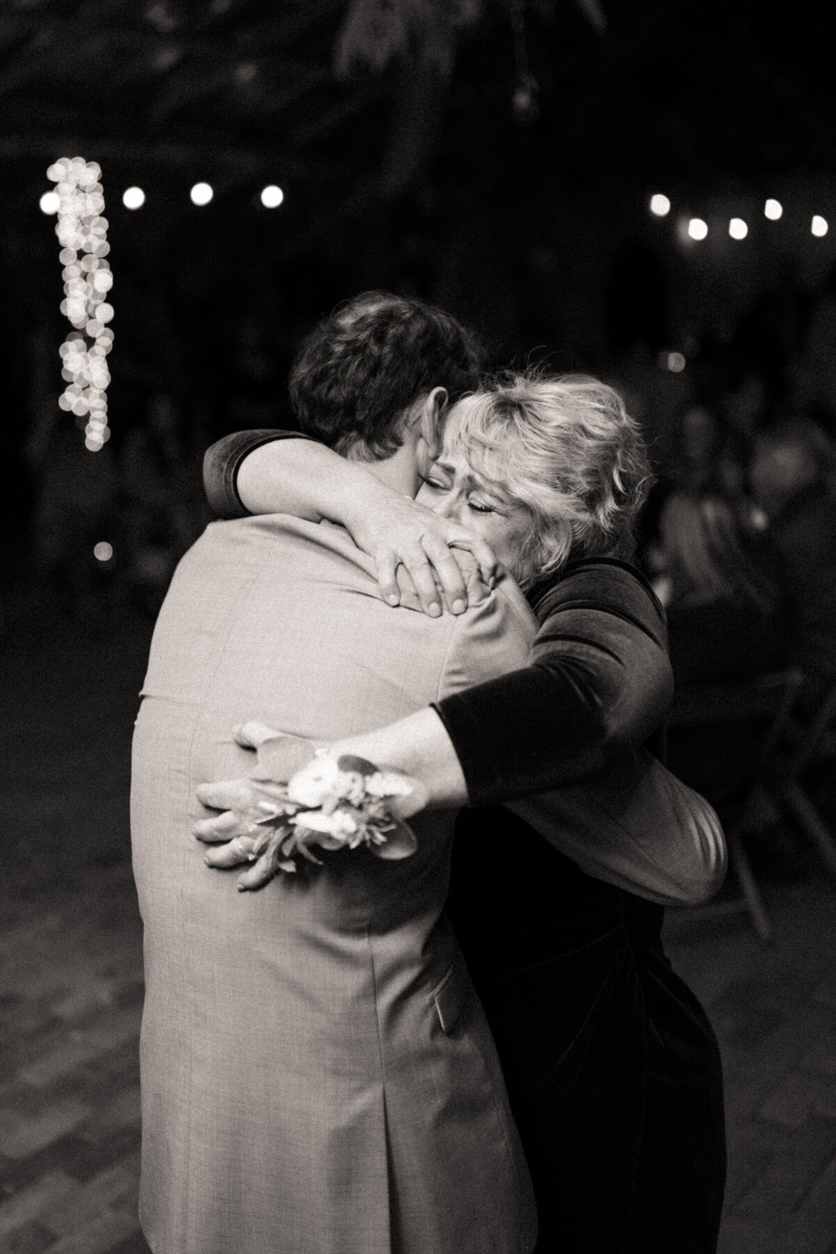 Mother of the groom tightly hugging the groom while crying and getting emotional during the mother son dance at a wedding reception