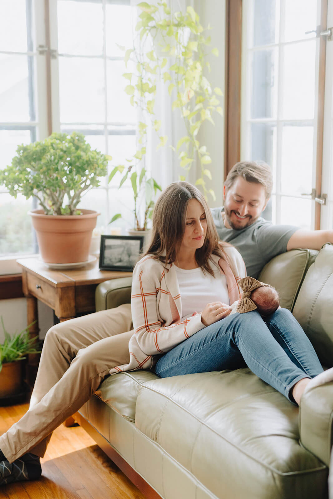 Couple sitting on sofa looking at newborn baby at newborn photoshoot at Finger Lakes, NY