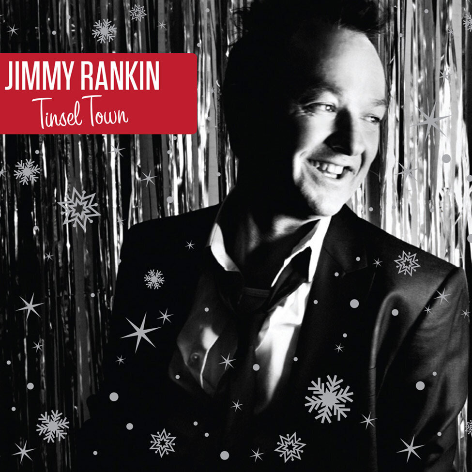 Christmas Album Cover Title Tinsel Town Artist Jimmy Rankin black and white portrait wearing suit and smiling against silver backdrop snowflakes superimposed in front of him