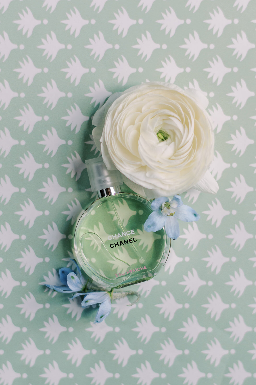 Chanel perfume surrounded by soft blue and white flowers.