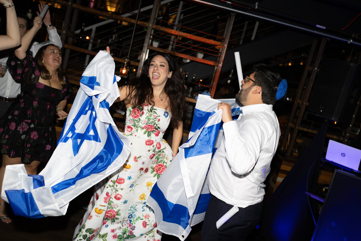 A couple celebrates their wedding by dancing with Jewish flags 