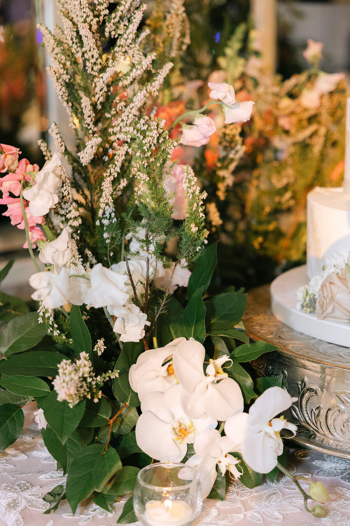 close up photo of floral arrangements around wedding cake candid moment of a guest dancing atThe Adolphus in Dallas