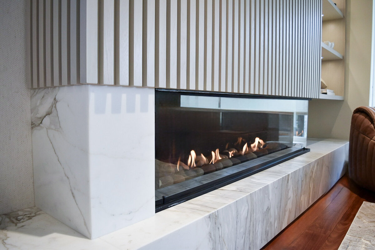 detail of linear gas fireplace, millwork surround, and marble hearth in ranger crescent renovation