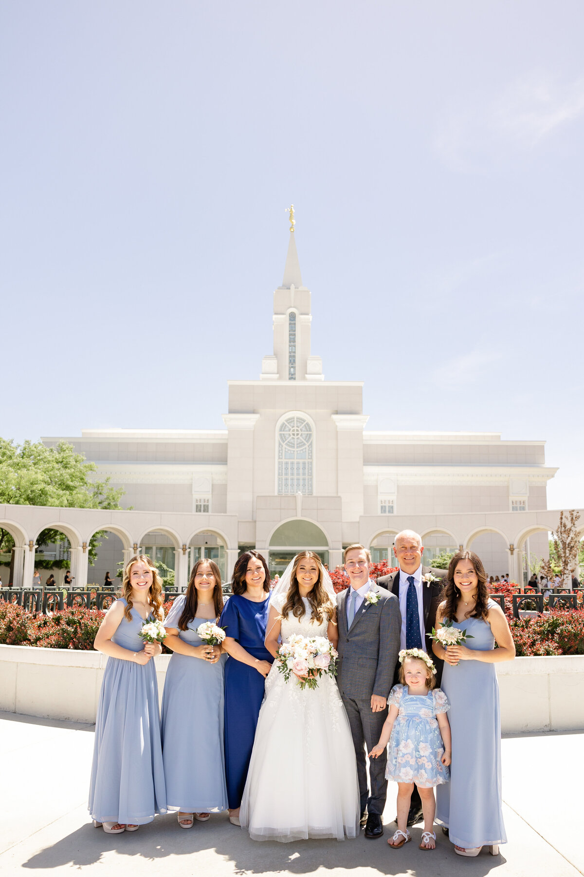 The bride and groom pose with their close family and bridal party in front of the elegant temple. Take by Cassie Lee Photography