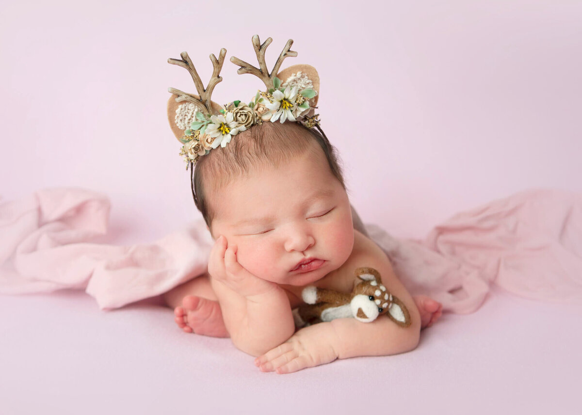 Baby born near Christmas in Los Angeles, asleep wearing a reindeer headband and holding a tiny reindeer teddy taken by Los Angeles Newborn Photographer Elsie Rose Photography