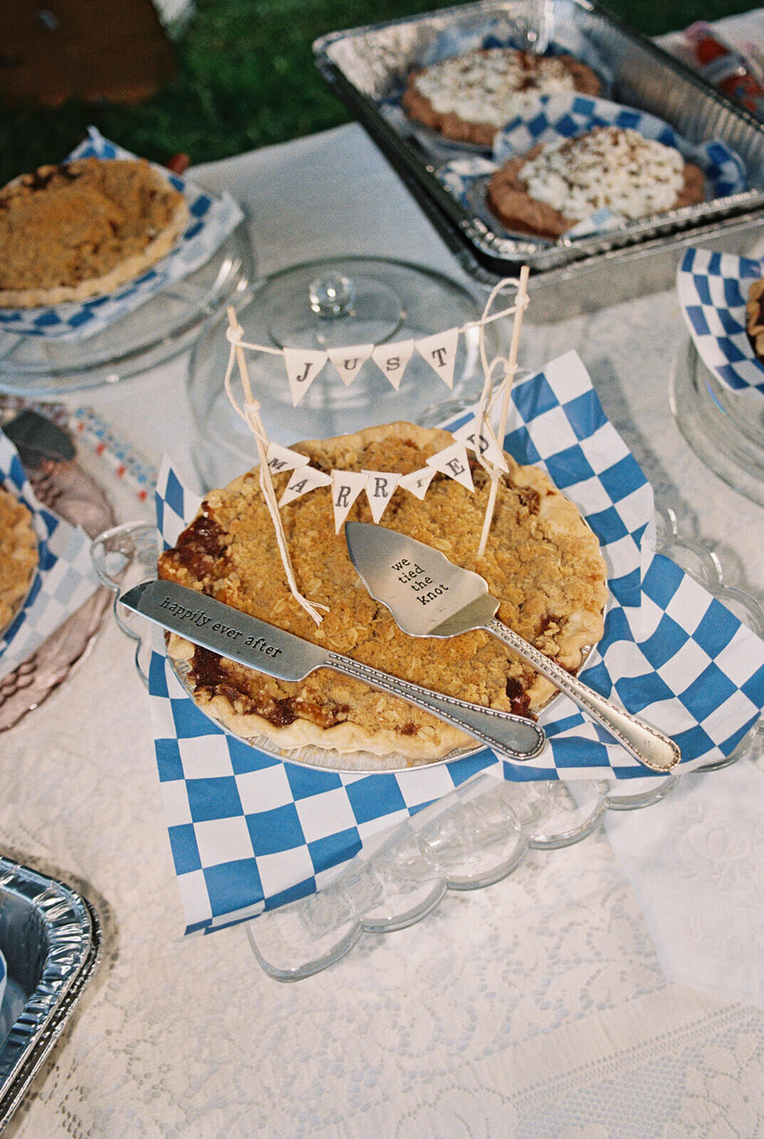 A pie at a wedding reception with a banner that says just married and serving cutlery.