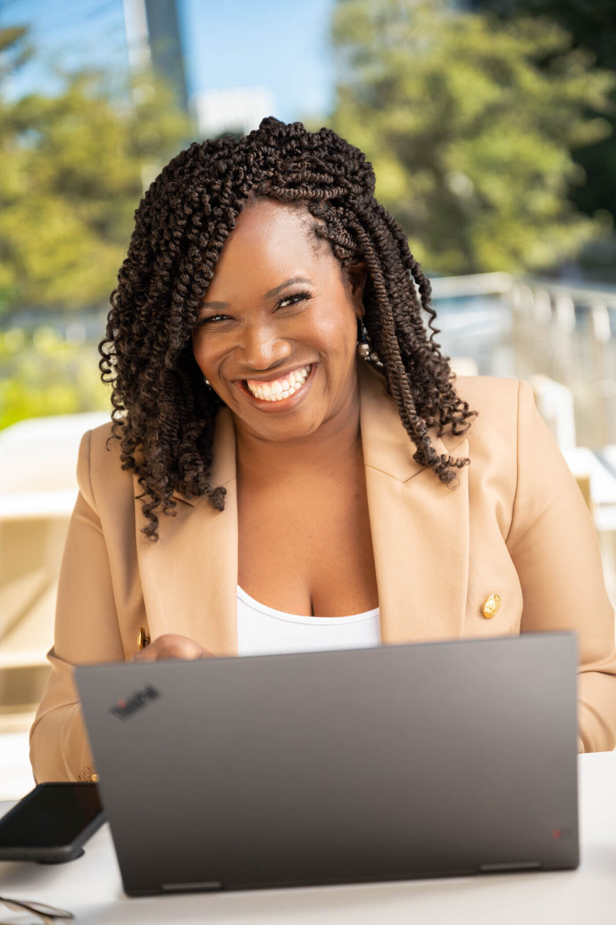A portrait of a woman with a big smile working on her laptop