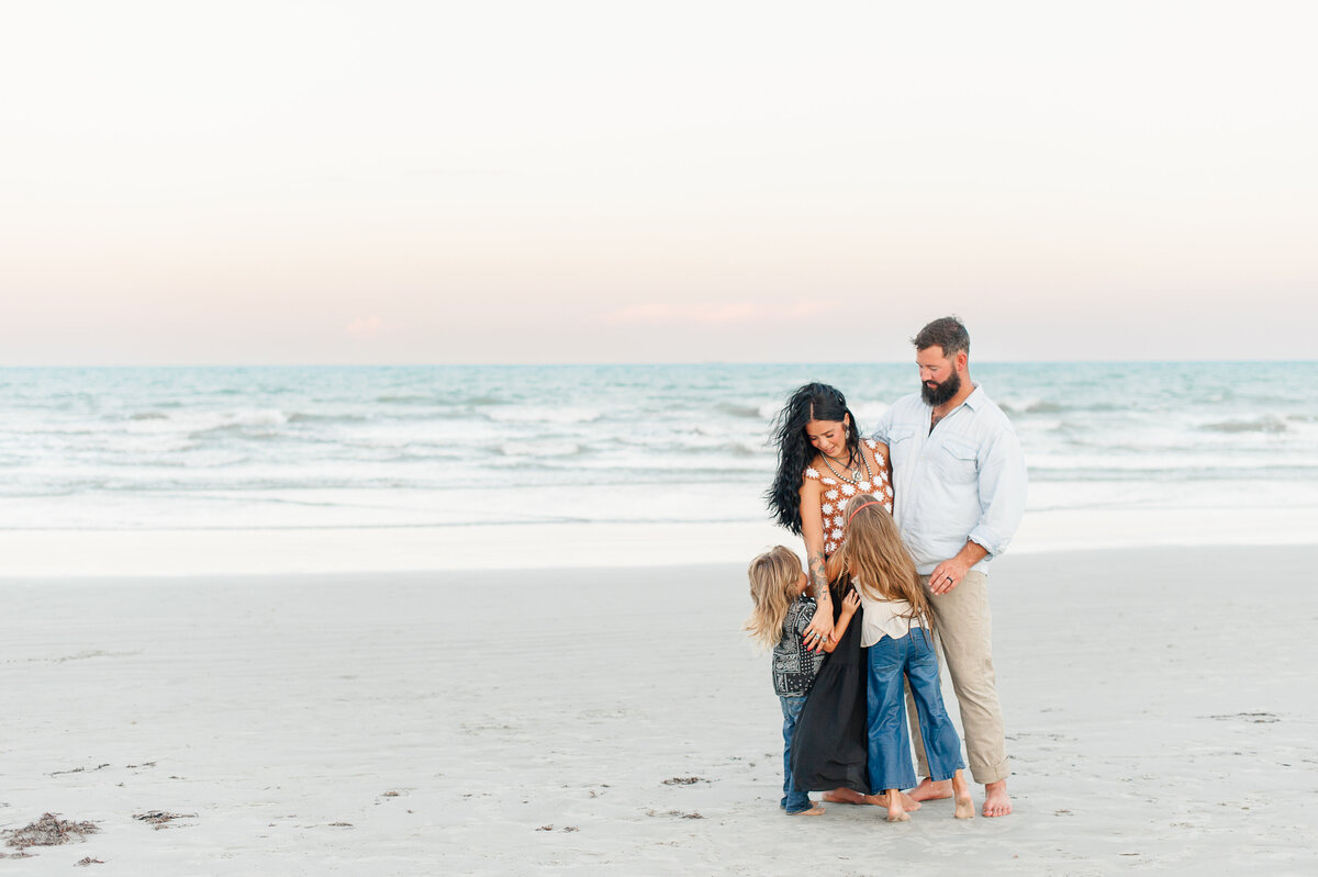 Family hugging on the beach near the ocean  at sunset