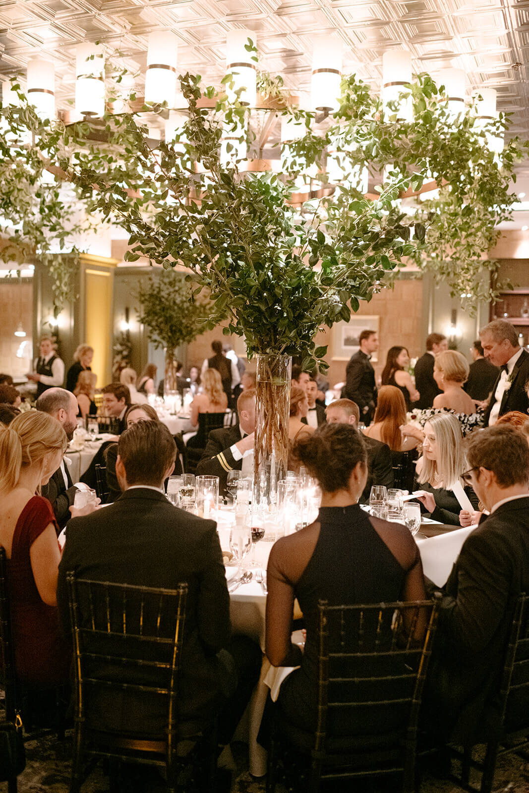 Beautifully lit dining room featuring towers of greenery at the St. Regis Aspen wedding reception.