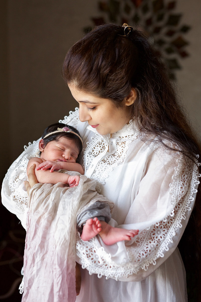 Mom is holding baby girl in her hands at home photo session in Calgary Alberta