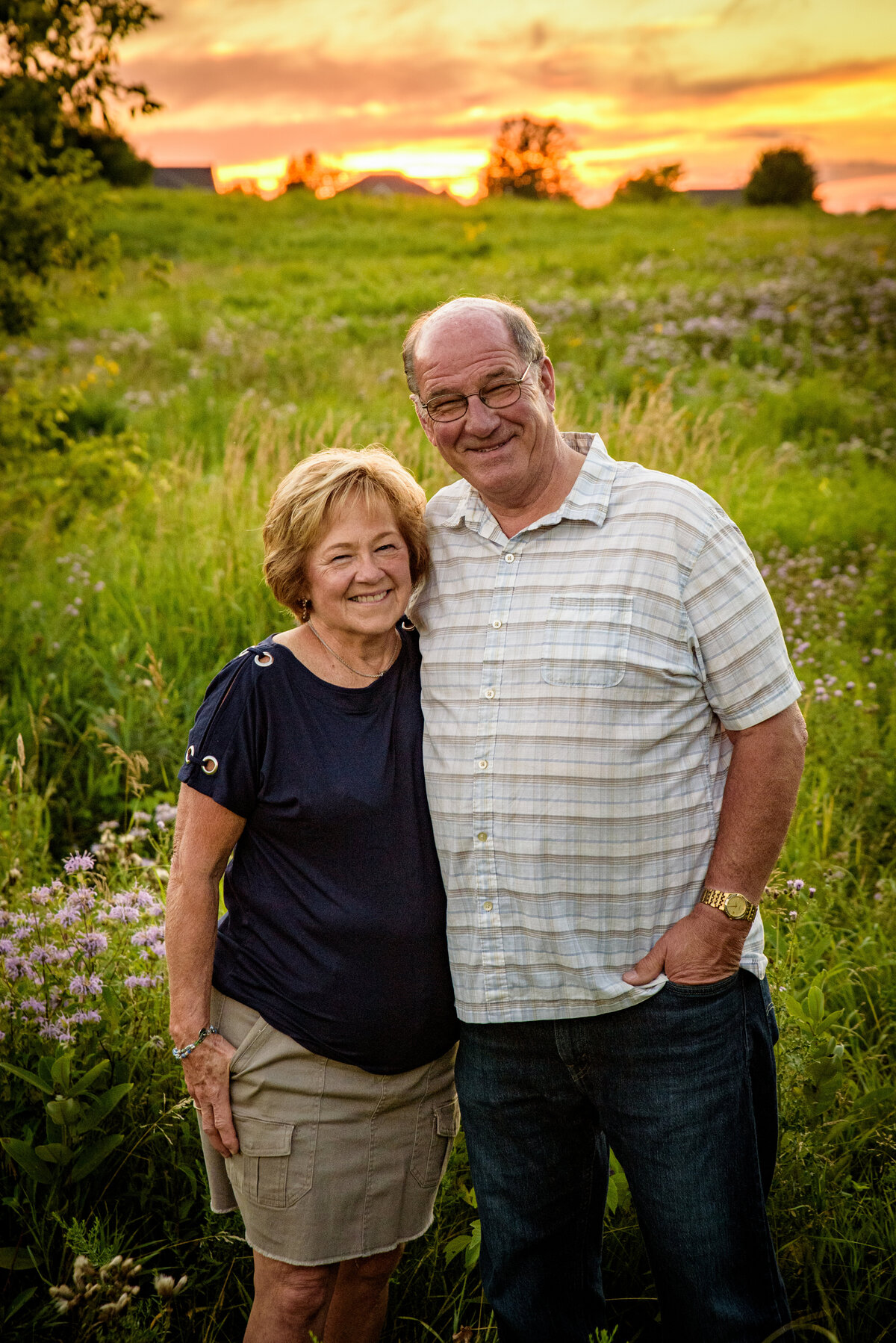 Portrait of grandparents standing in grassy area  with beautiful sunset at Fonferek Glen County Park near Green Bay, Wisconsin