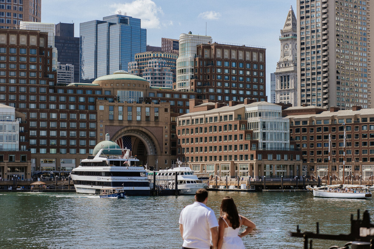 Boston proposal: Couple at Fan Pier Park looking out towards the water and buildings