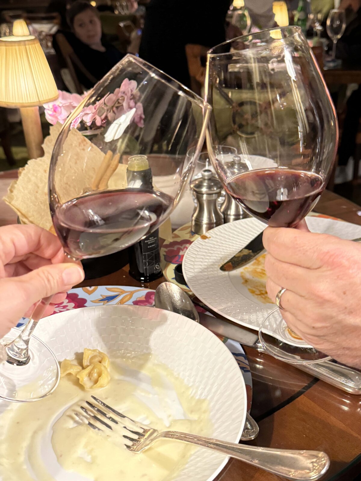 Wine glasses clinking over a finished dinner in a restaurant 