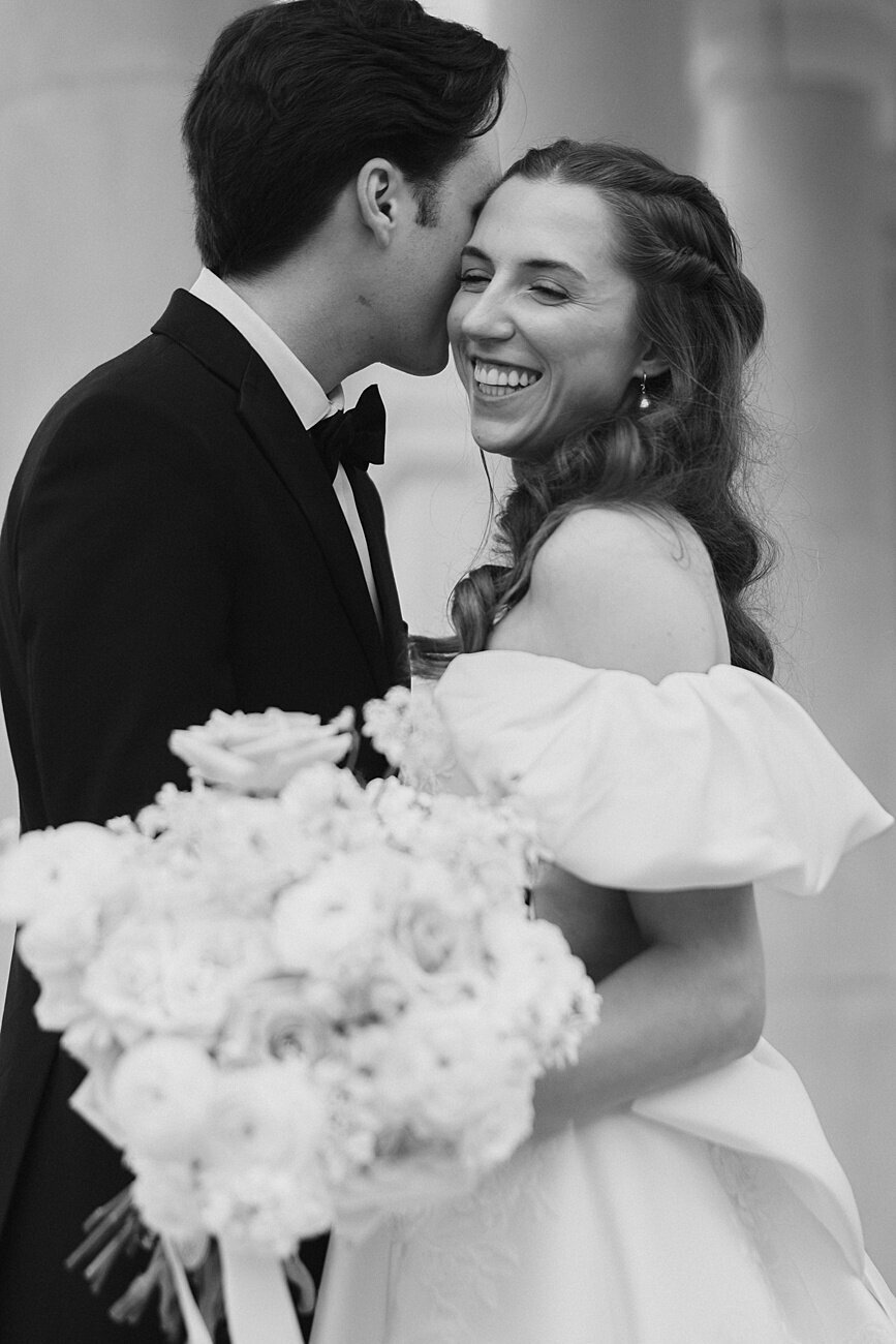 Groom whisper in bride's ear as she laughss