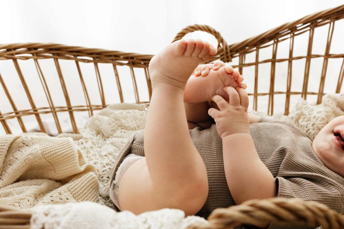 Ruua Hamdan Photography (Altrincham/Manchester, UK): A baby lies awake in a blanket-lined bassinet, with their feet raised