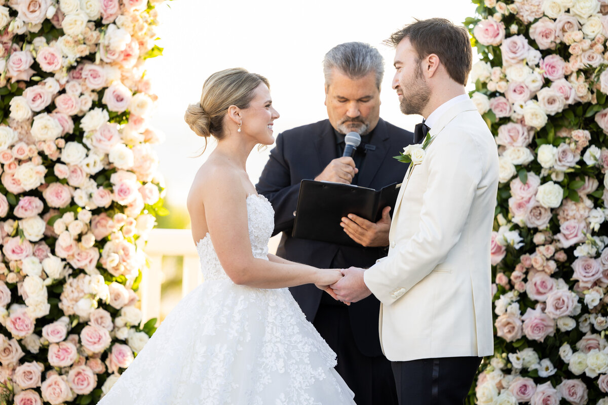 bride and groom under arch of roses