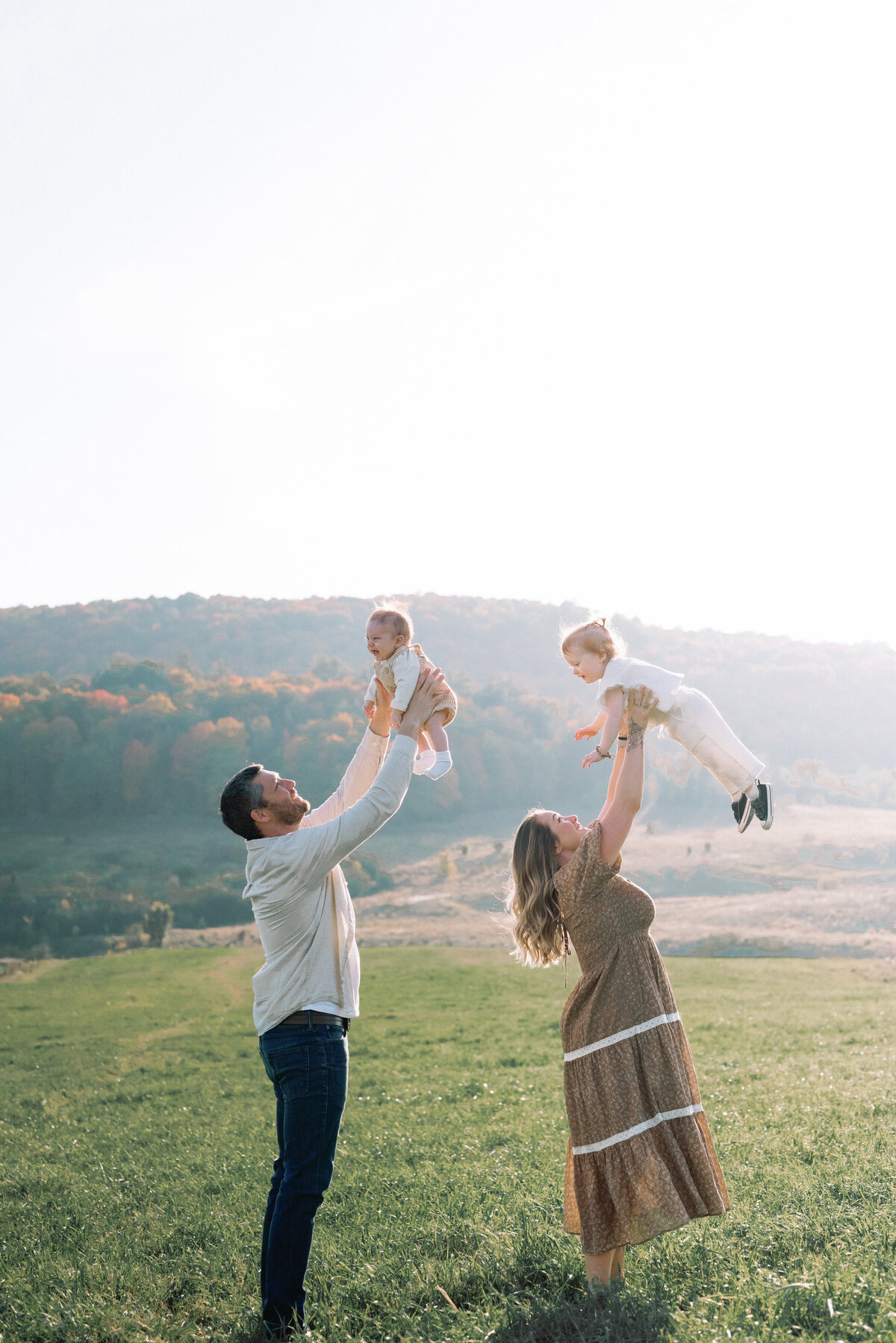 Family of four with parents throw children up in the air with big laughs