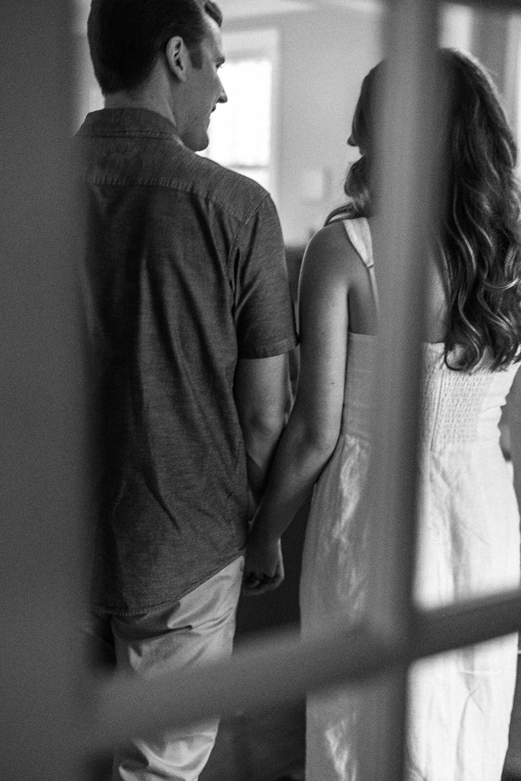 A couple holding hands are captured from behind through a window pane. 