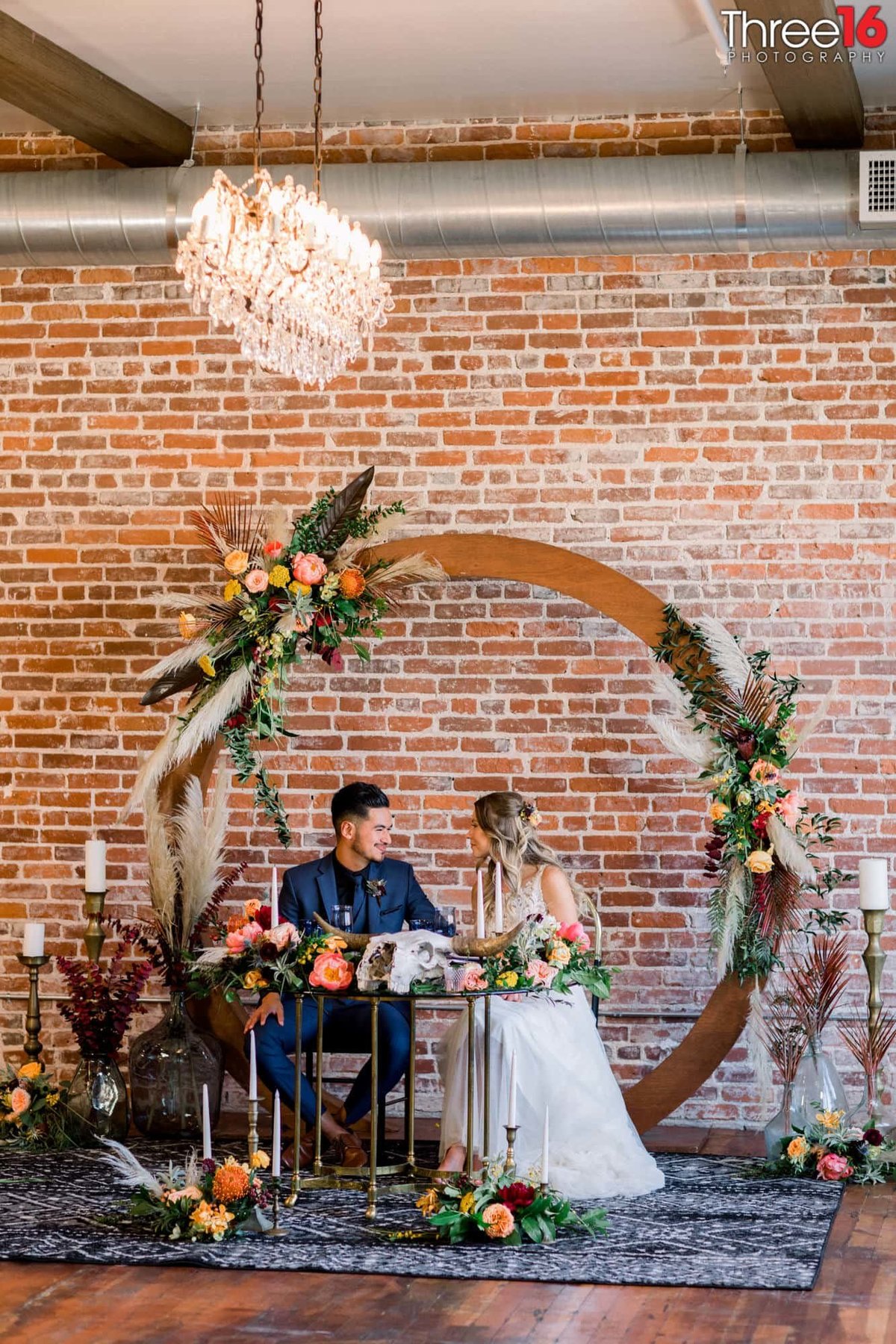 Bride and Groom sit at the Sweetheart Table gazing into each others eyes