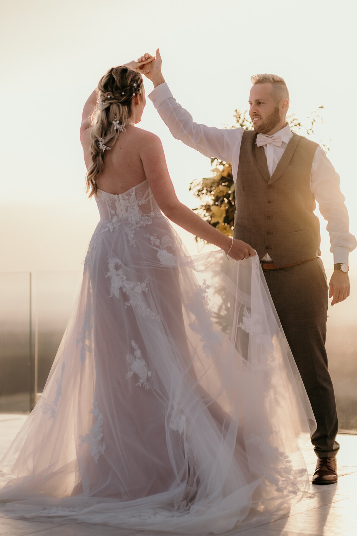 Die Braut hält mit einer Hand ihr Kleid, während der Bräutigam sie im Kreis dreht.