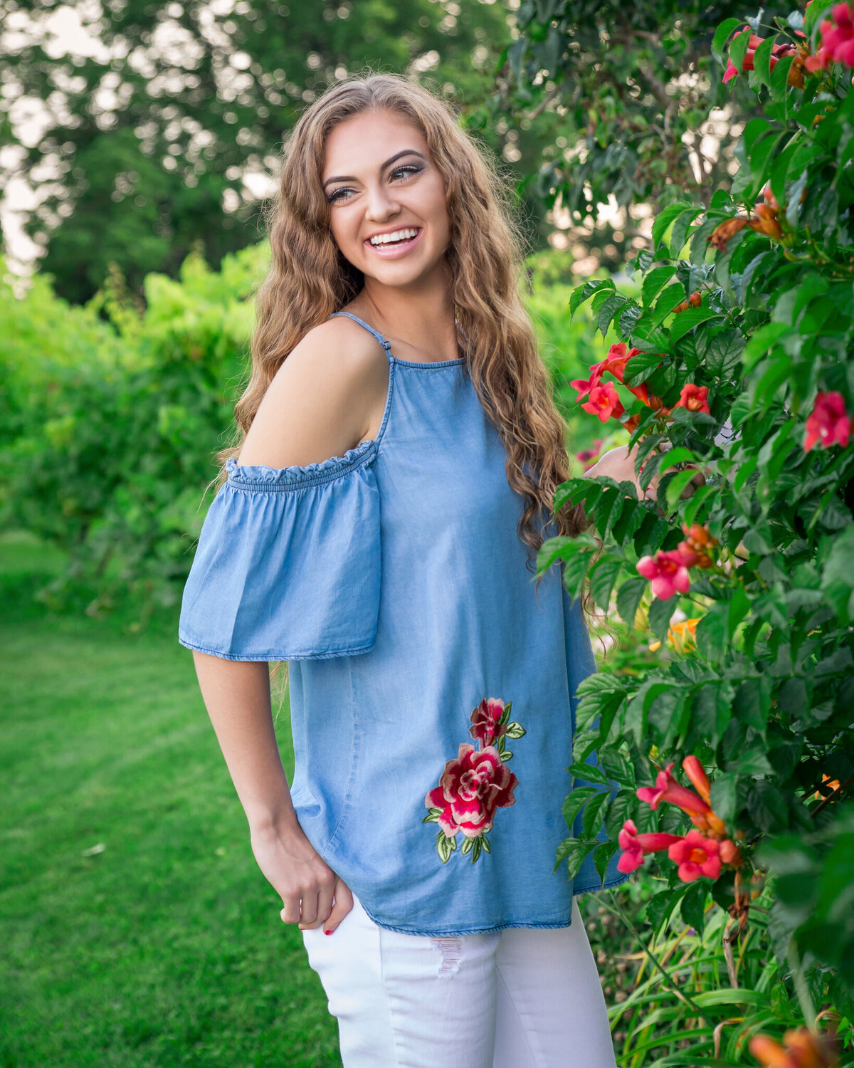 Senior girl by a flower bush in a garden