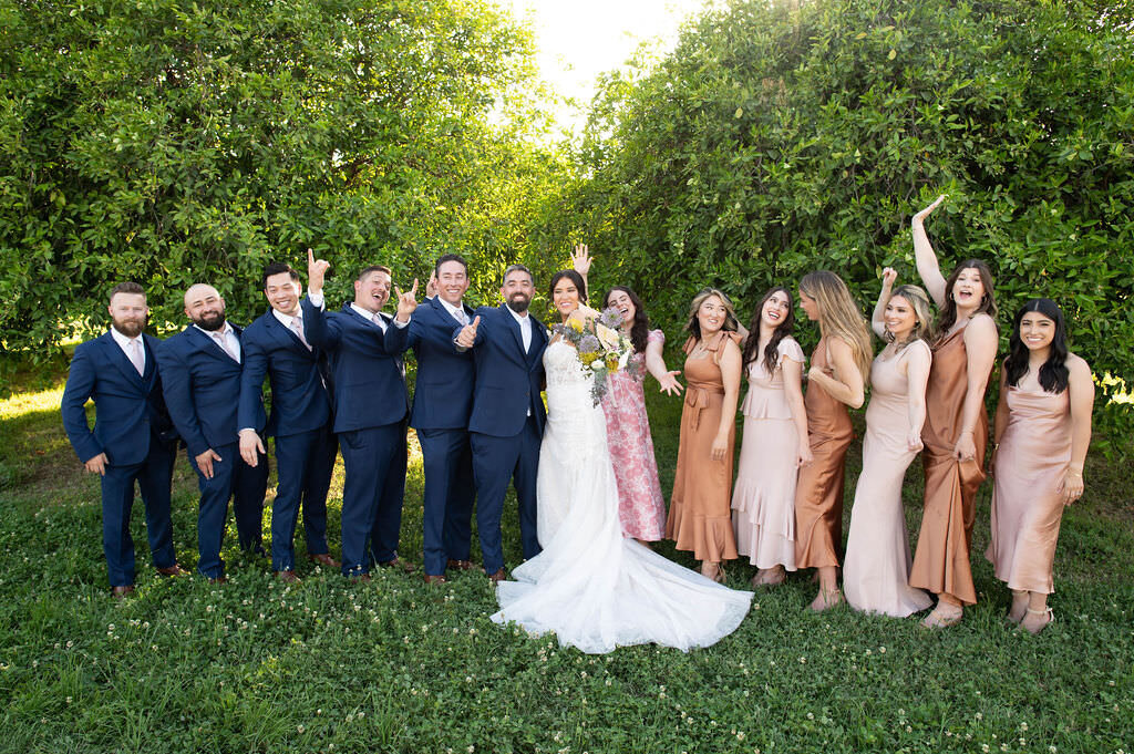 A bride and groom smiling with their wedding parties on either side of them