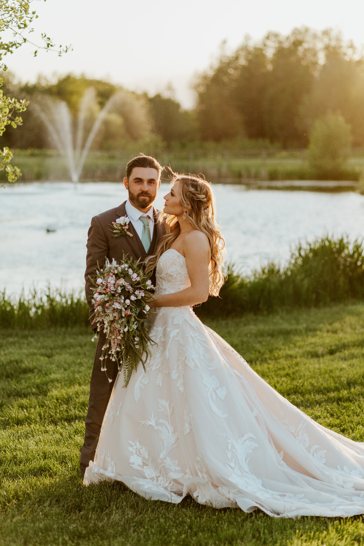 bride and groom posing by lake