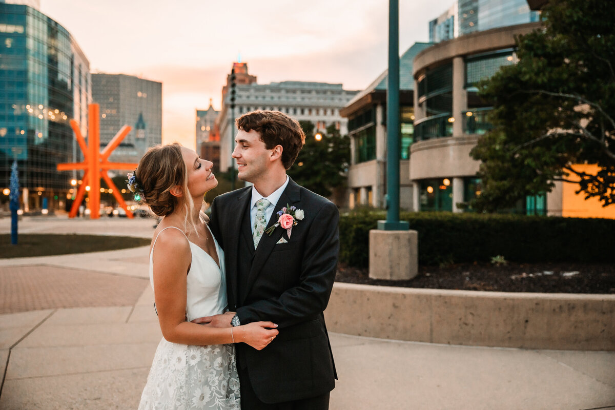 A bride and groom hug and laugh while exploring downtown Milwaukee