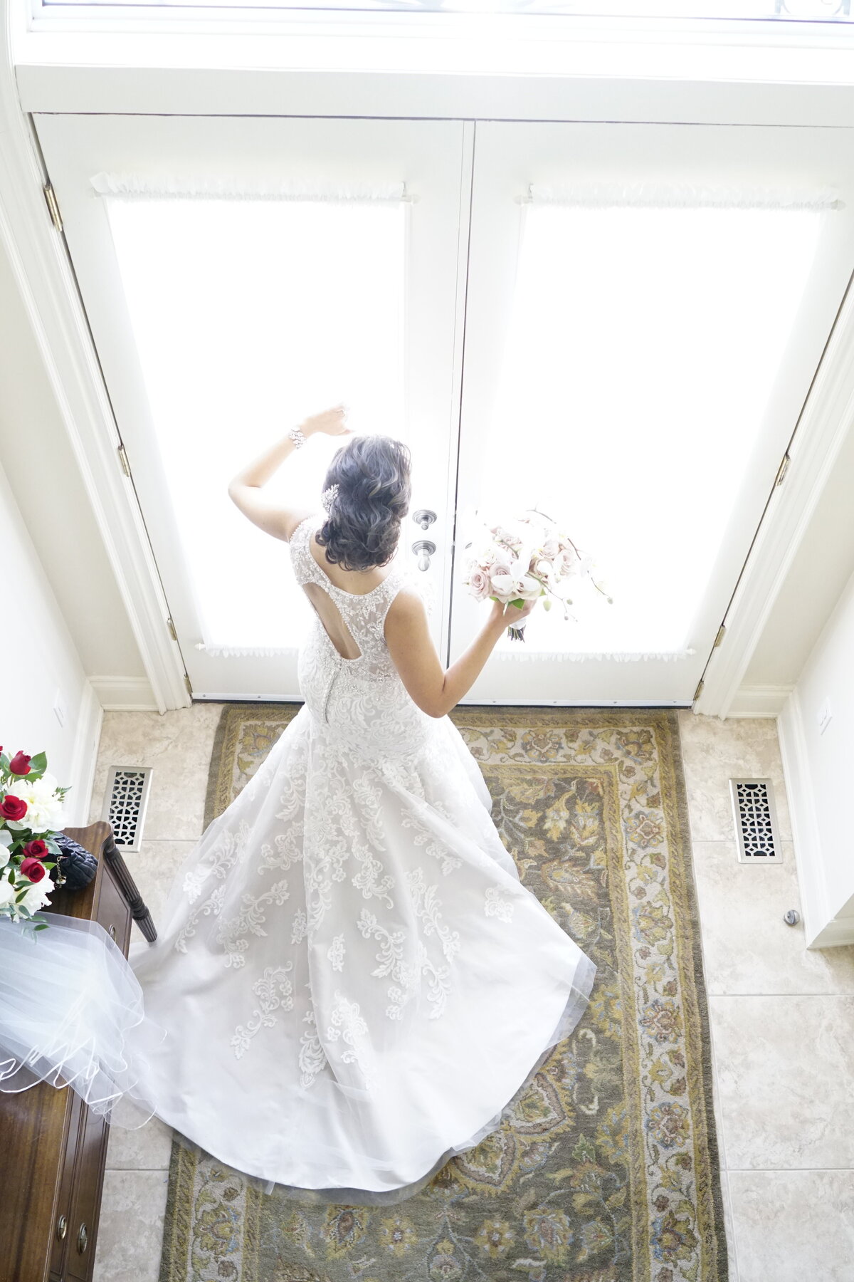 A bride makes a grand entrance in her wedding dress, capturing the elegance and drama of the moment. This image showcases the intricate details of her gown and the captivating presence of the bride as she steps into the spotlight, highlighting the grandeur of her special day.