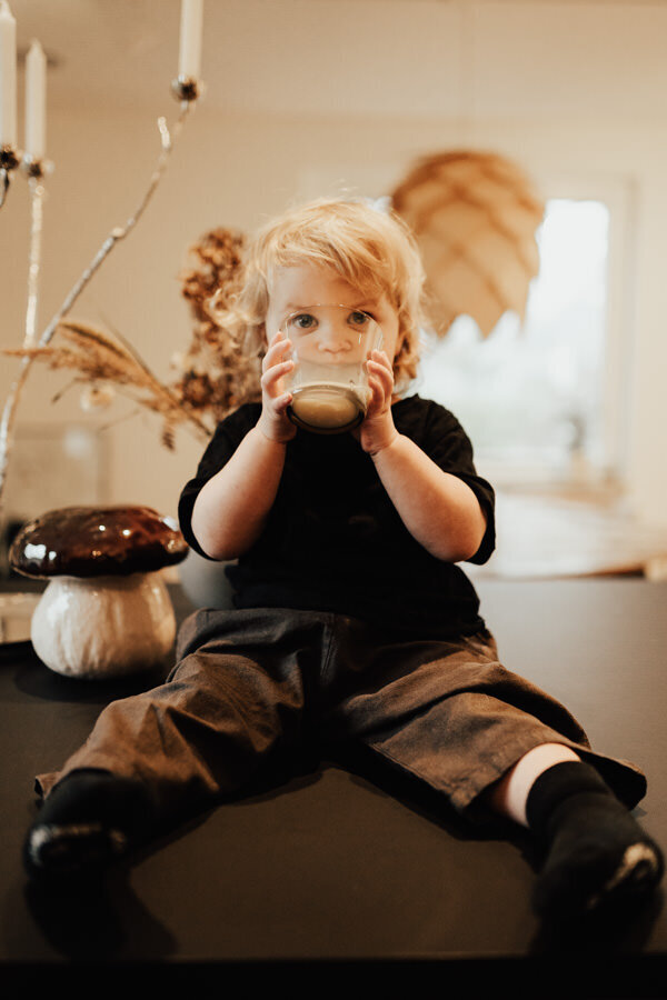 barn sitter på köksö och dricker mjölk under lifestylefotografering