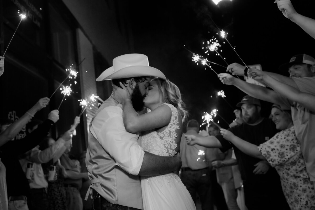 grand exit at the end of the wedding night with bride and groom kissing passionately as their wedding guests wave sparklers around them