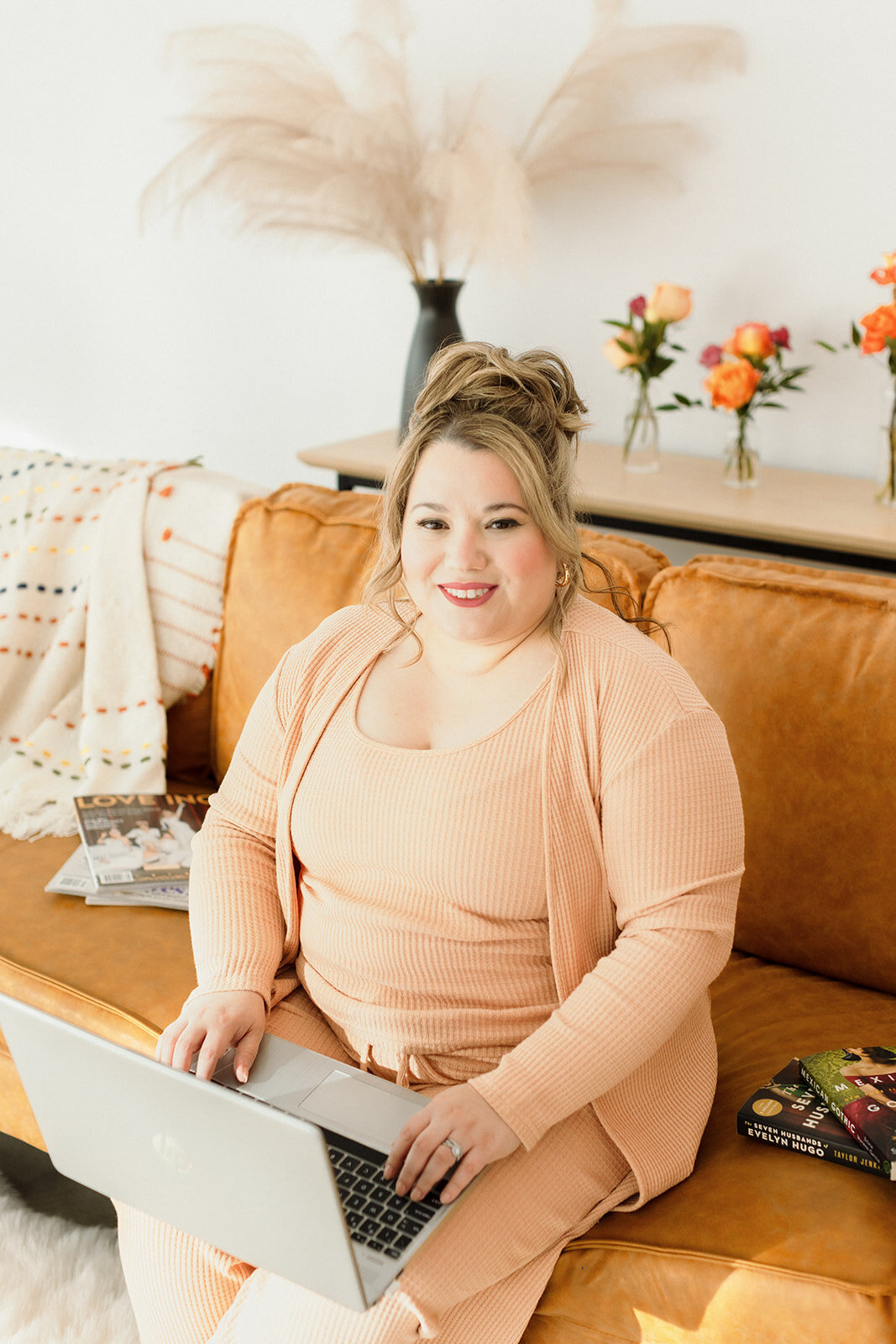 close up of woman working at her laptop on orange couch and smiling