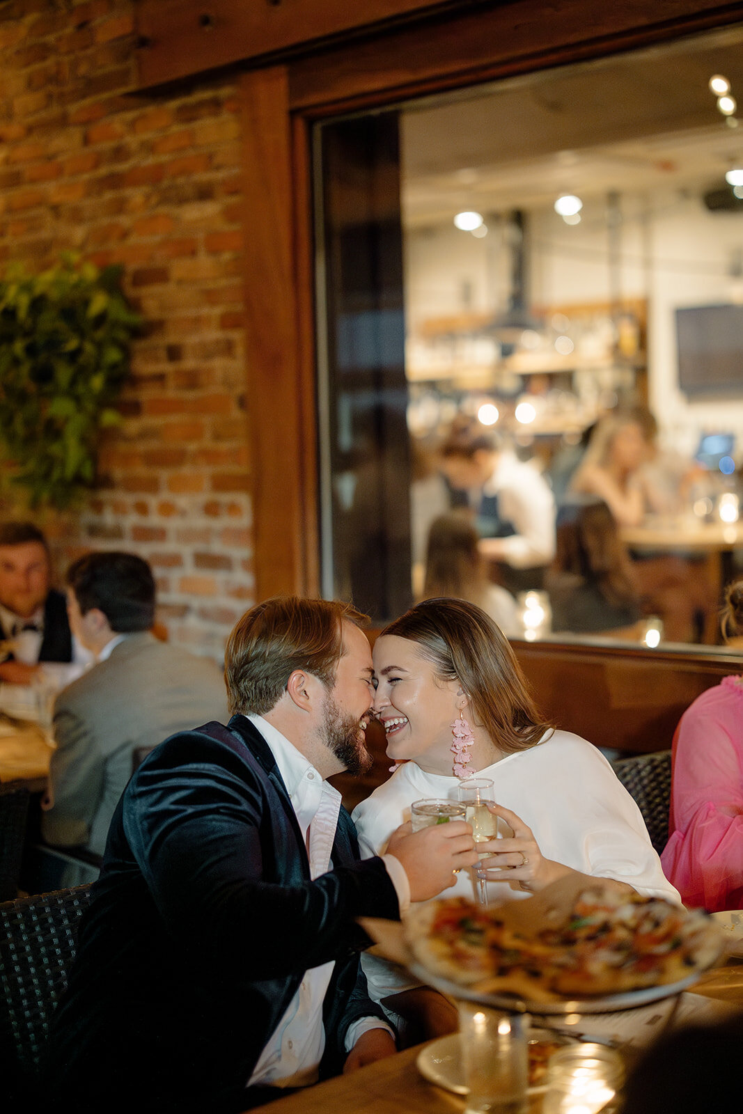 Bride and groom touching heads while laughing with each other and clinking glasses