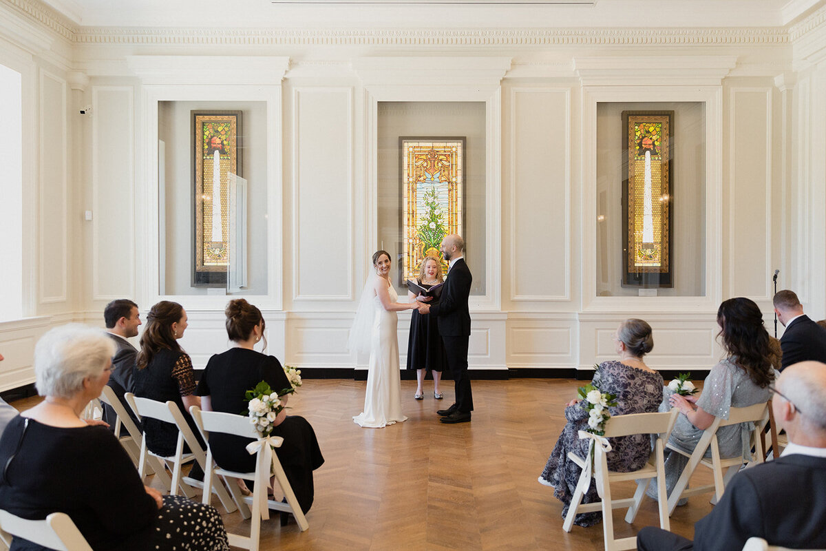 The wedding couple holds hands during the ceremony and looks out to their guests.